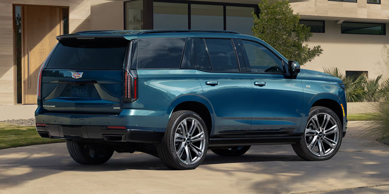 Teal luxury SUV parked in a driveway, rear side view.