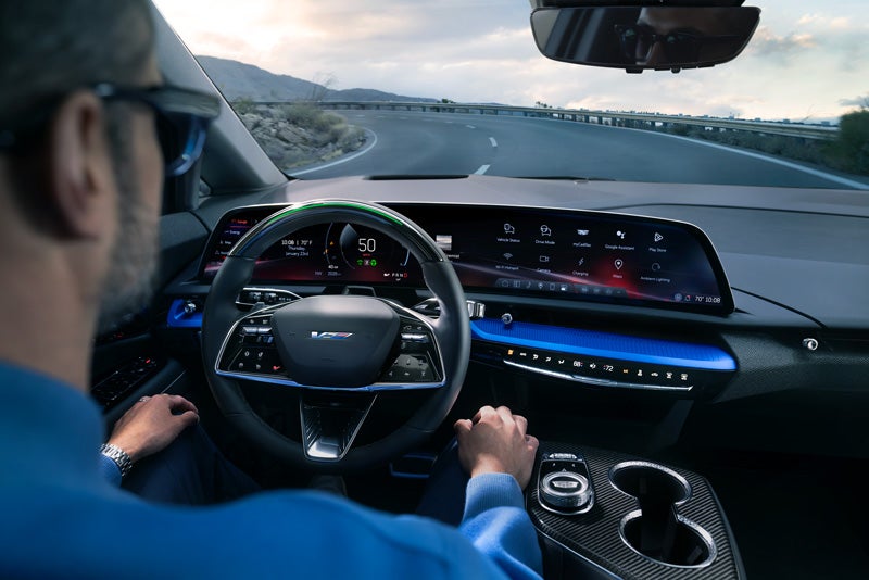 Front View of the 2026 OPTIQ-V Driving Through the Dusk Utilizing its Headlights | Alexander Cadillac in Oxnard CA