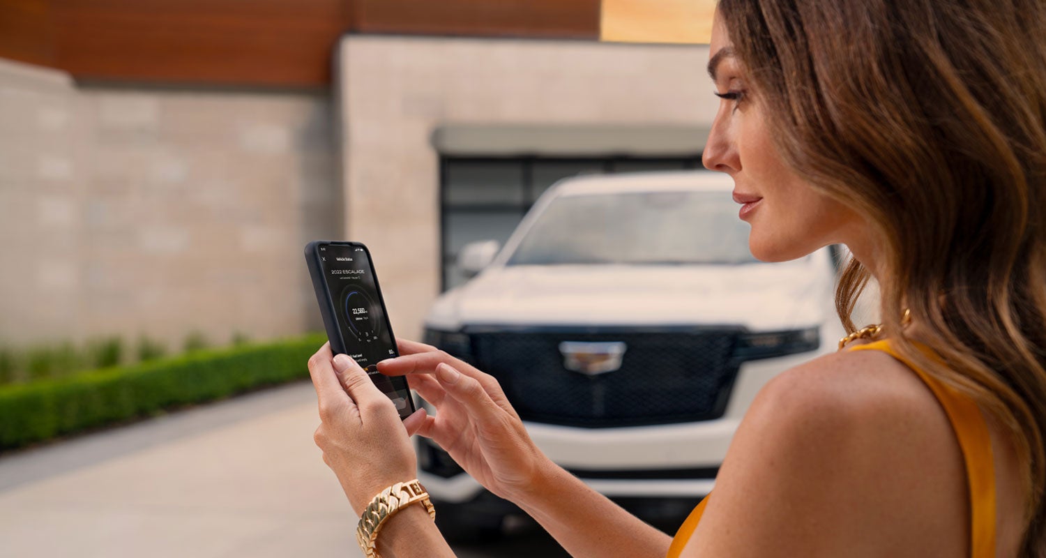 lady checking her mobile with a Cadillac vehicle background | Alexander Cadillac in Oxnard CA
